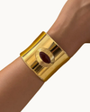 Matilde Cuff by Heaven Mayhem in gold with a deep burgundy enamel center and bold architectural design.
 Copy alt text