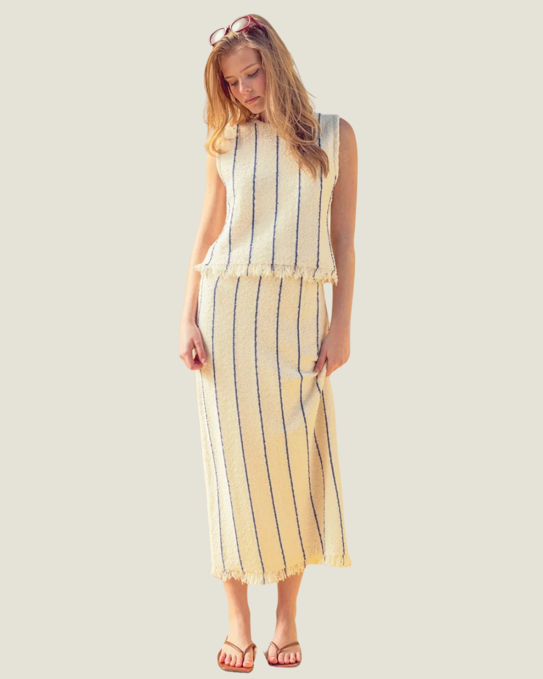 Cream knit midi skit with blue stripes and a fringe hem, part of a matching set. 